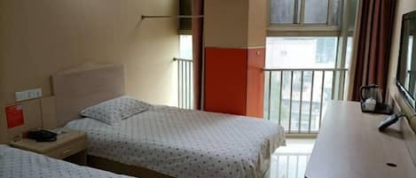 A hotel room with two beds, a desk, a window with a view, and a balcony.