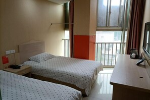 A hotel room with two beds, a desk, a window with a view, and a balcony.