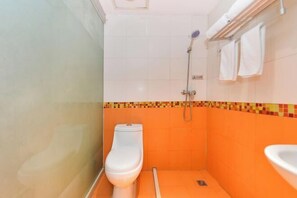 A small bathroom with a toilet, a shower, and a sink.