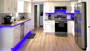 A modern kitchen with white cabinets, a stainless steel refrigerator, and a built-in oven. - Tampa Luxury 5BR Estate with Pool + Golf Views (Tampa)