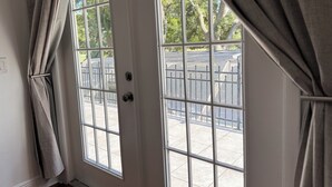 A white door with a grid pattern, a metal handle, and a view of a parking area with a fence and trees outside. - Tampa Luxury 5BR Estate with Pool + Golf Views (Tampa)