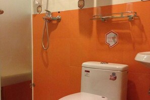 A bathroom with an orange wall, a white toilet, and a shower with a handheld showerhead. - 99 Inn (Shanghai Liuying Road) (Shanghai)