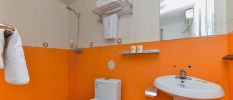 A bathroom with a white toilet, an orange wall, a white sink, and a towel rack with a towel.