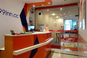 A reception desk with a computer, a phone, and a small table with items on it. - 99 Inn (Shanghai Liuying Road) (Shanghai)