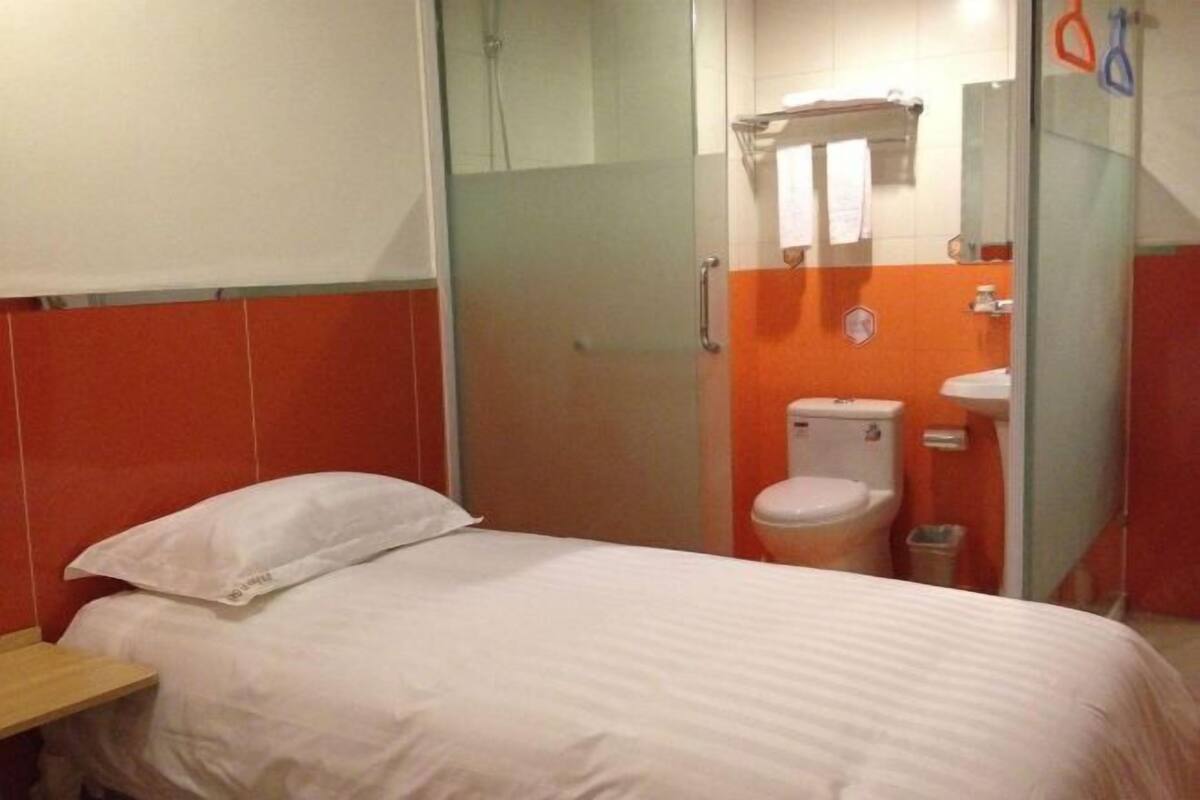 A hotel room with a bed, a shower, and a toilet.