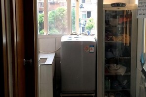 A compact room with a window, a small desk, a refrigerator, and a glass cabinet with shelves. - 99 Inn (Shanghai Liuying Road) (Shanghai)