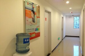A hallway with a water dispenser, a poster, and a door at the end. - 99 Inn (Shanghai Liuying Road) (Shanghai)