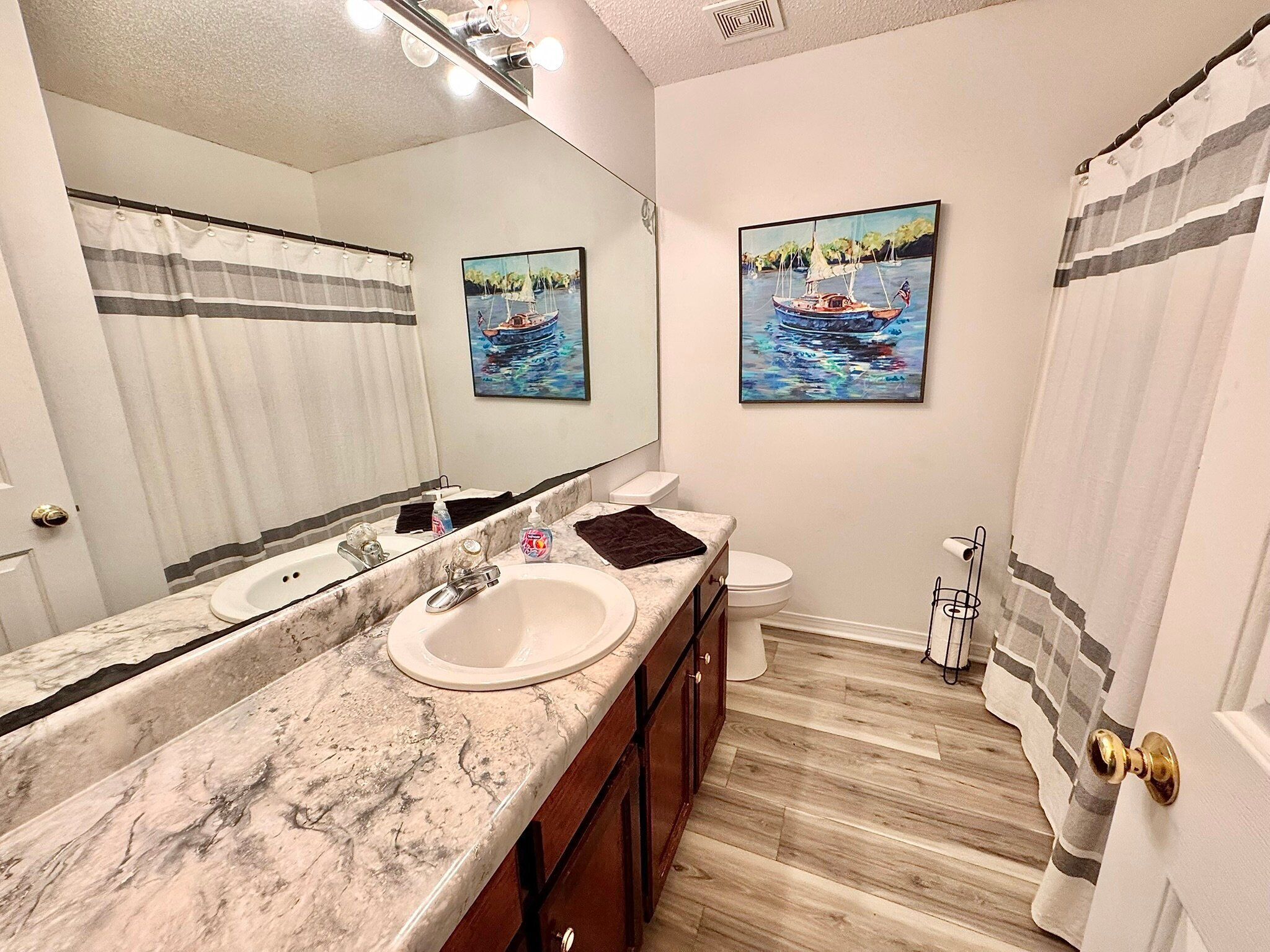 Un bagno con un lavandino in marmo, un water e due quadri appesi al muro.