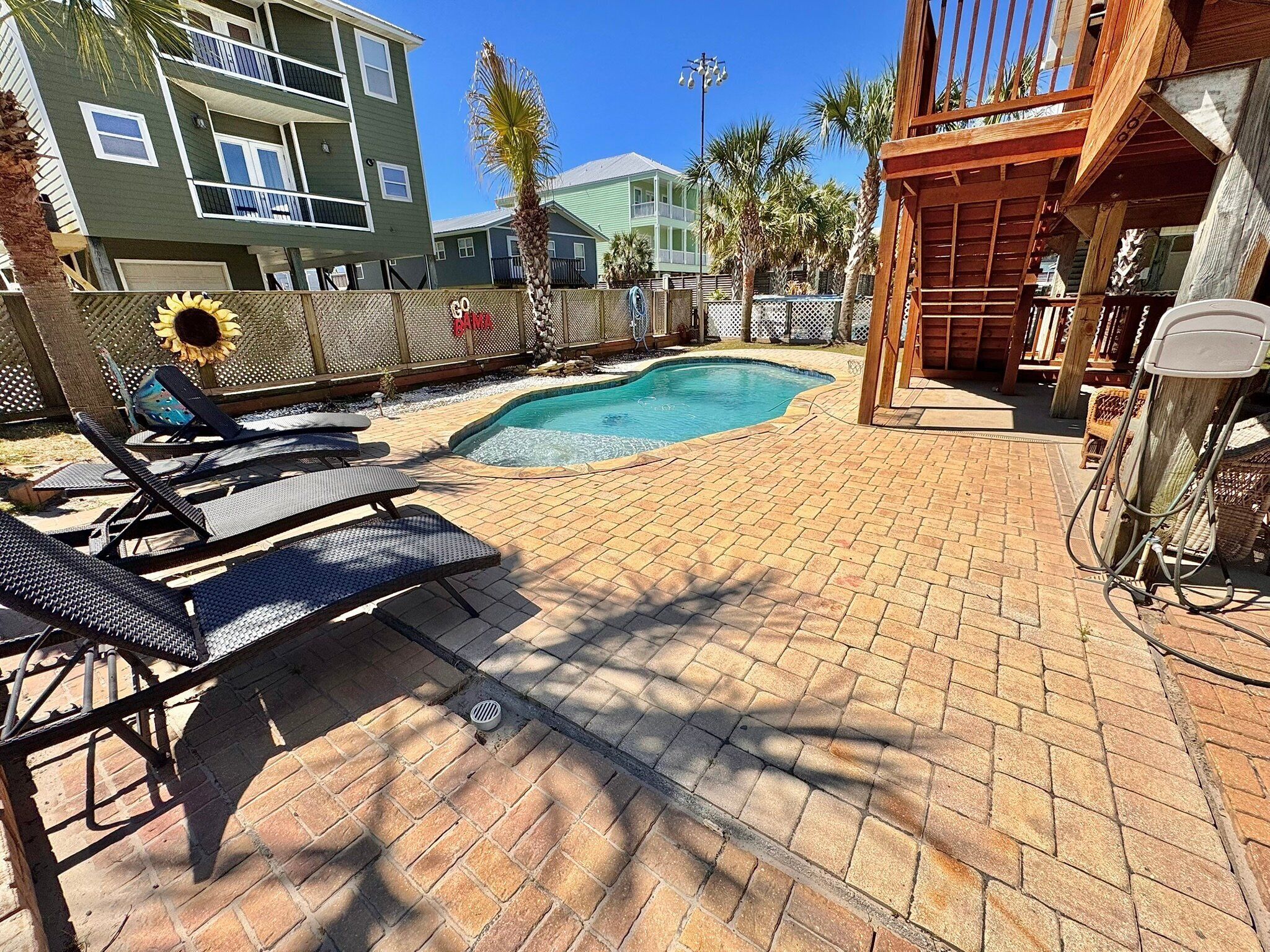 A pool area with lounge chairs, a wooden pergola, and a clear blue sky.