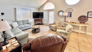A living room with a sofa, armchair, coffee table, and a ceiling fan.
