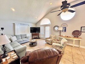 Relax in this stylish living room with a comfortable sofa, leather chair, and mounted TV.