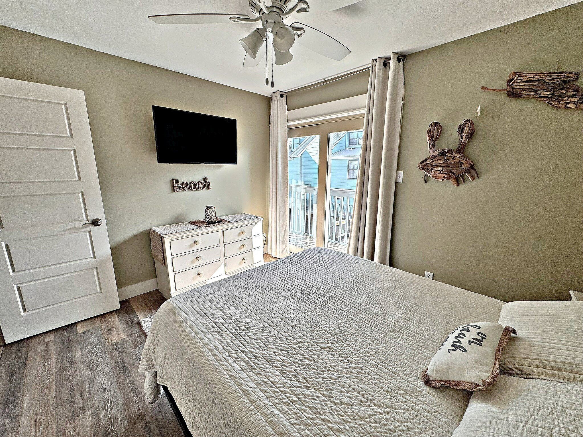 Ein Schlafzimmer mit Bett, Kommode, Fernseher und Blick ins Freie.
