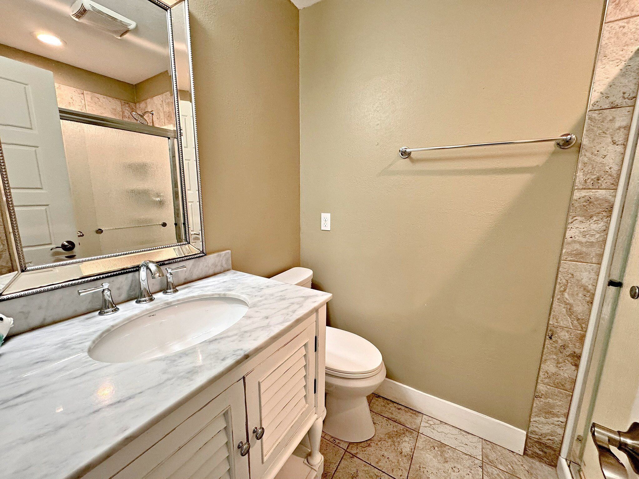 Une salle de bain avec un lavabo en marbre, des toilettes et un espace douche.