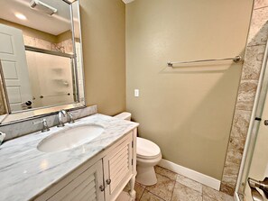 Baño con lavabo de mármol, inodoro y zona de ducha.