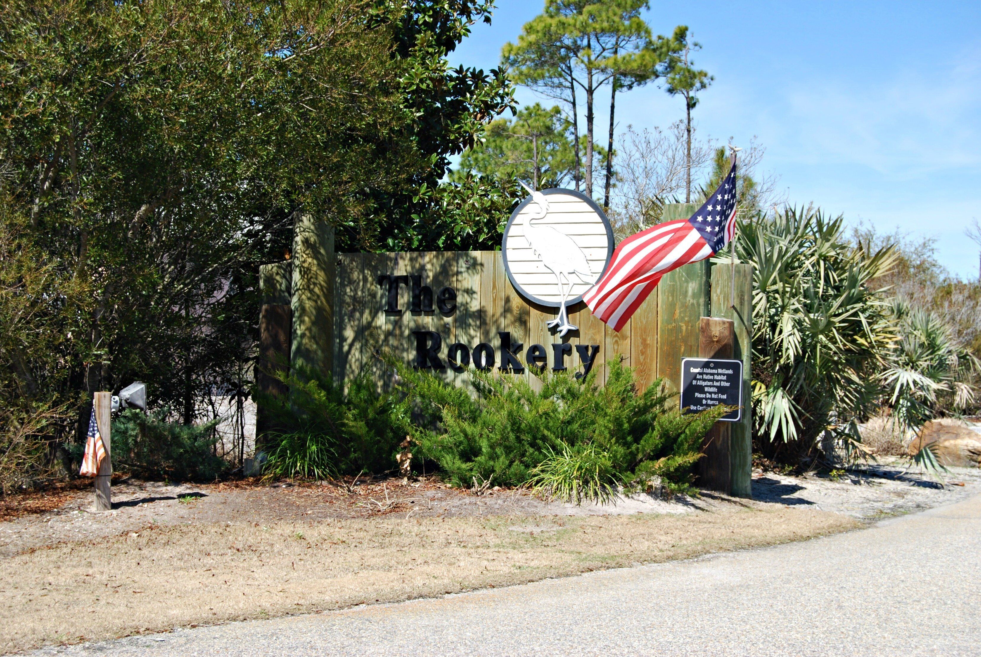 A wooden sign with "The Rookery" written on it, an American flag, and a sign with a message about no pets allowed.