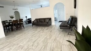 A spacious living area with a sofa, a dining table with chairs, and a large plant.