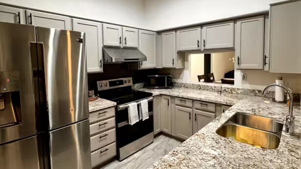 A modern kitchen with stainless steel appliances, granite countertops, and white cabinetry.