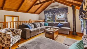 A cozy living room with a wooden ceiling, a sofa set, a patterned armchair, and a coffee table. - StayAU Luxury Candlewick Cottage in Dandenong (Mount Dandenong)