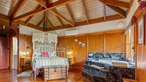 A spacious bedroom with a large bed, a wooden ceiling, and a bathroom with a marble countertop.
