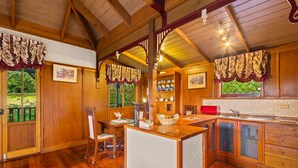 A wooden interior with a kitchen area, dining table, and chairs.