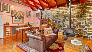 A cozy living room with a stone wall, wooden furniture, and a fireplace. - StayAU Owls Croft Picturesque Cottage Valley View (Mount Dandenong)
