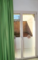 Une pièce dotée d’une porte-fenêtre coulissante donnant sur un espace extérieur avec vue sur un pont et un mur recouvert de carreaux.