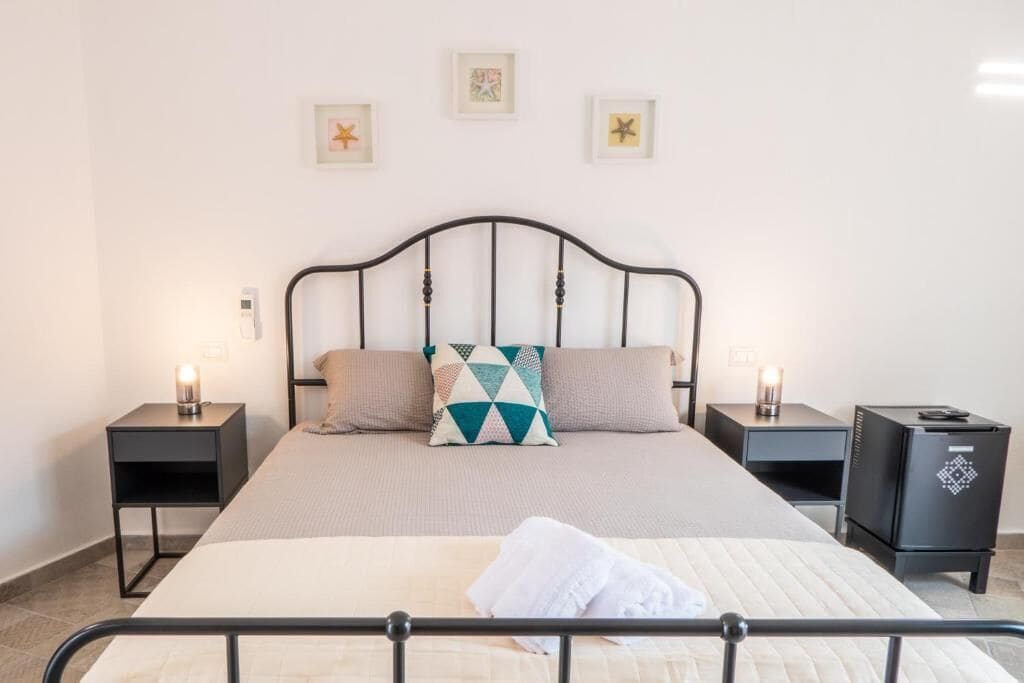 Ein ordentlich eingerichtetes Schlafzimmer mit einem Bett, zwei Nachttischen und einem Schreibtisch.