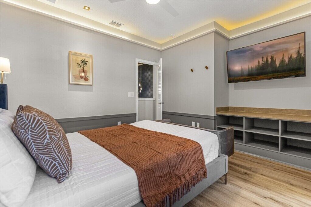 Um quarto moderno com uma cama, uma televisão e uma estante.