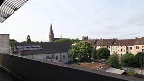 A residential area with a church spire, solar panels on rooftops, and a variety of houses. - Livemore24 - Apartment 2 in Duisburg 24/7 check-in (Duisburg)