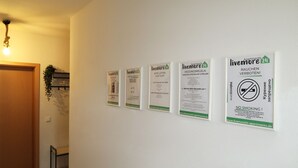 A hallway with five signs on the wall, including a no smoking sign and others with contact information and rules. - Livemore24 - Apartment 2 in Duisburg 24/7 check-in (Duisburg)