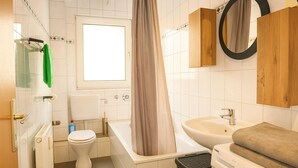 A bathroom with a toilet, bathtub, sink, and a window. - Livemore24 - Apartment 2 in Duisburg 24/7 check-in (Duisburg)
