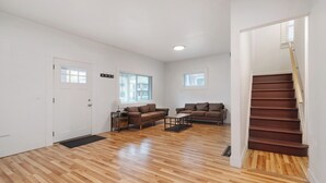 A spacious living room with a wooden floor, two sofas, a coffee table, and a staircase.