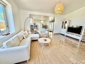 A modern living room with a sectional sofa, a round coffee table, and a flat-screen TV.