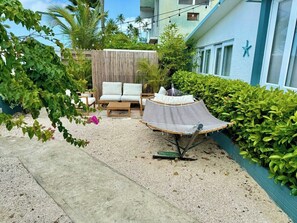A patio area with a hammock, a sofa, and a small table.