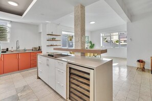 A modern kitchen with white cabinets, a built-in oven, and a central island with a sink. - Villa Coco: Private Pool | 5 Min Walk to Beach (San Juan)