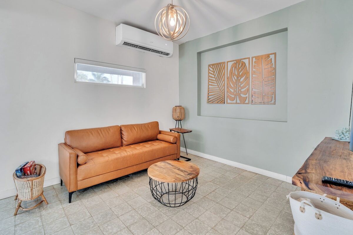 A living room with a leather sofa, a round coffee table, a floor lamp, and wall art.