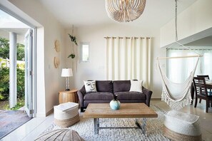 Una sala moderna con un sofá, una mesa de centro y una silla colgante.