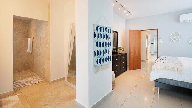 Een moderne slaapkamer met een bed, een dressoir en een douchegedeelte.