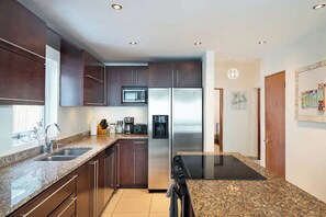 Una cocina moderna con gabinetes oscuros, electrodomésticos de acero inoxidable y encimeras de granito.