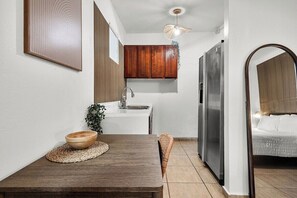 A compact kitchen with a wooden table, a sink, and a refrigerator.