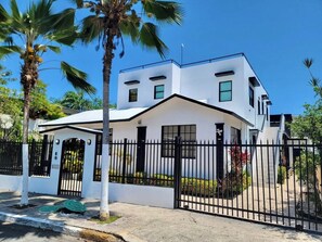 A modern two-story house with a white exterior, black gates, and a small covered porch.
