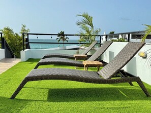 Outdoor lounge chairs with a view of the ocean.