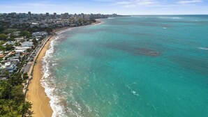 Un paysage urbain côtier avec une plage, des bâtiments et une vue dégagée sur l’océan.