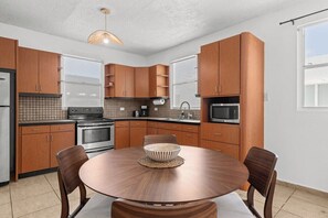Una cocina moderna con armarios de madera, una mesa redonda para comer y una lámpara colgante.