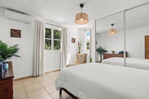 A bedroom with a large bed, a mirror, a window with curtains, and a ceiling fan.