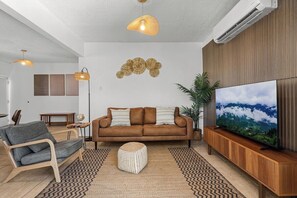 A modern living room with a sofa, a television, and a decorative wall piece.