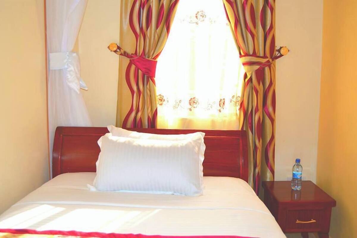 Une chambre d’hôtel avec un lit, une table de chevet et des rideaux.