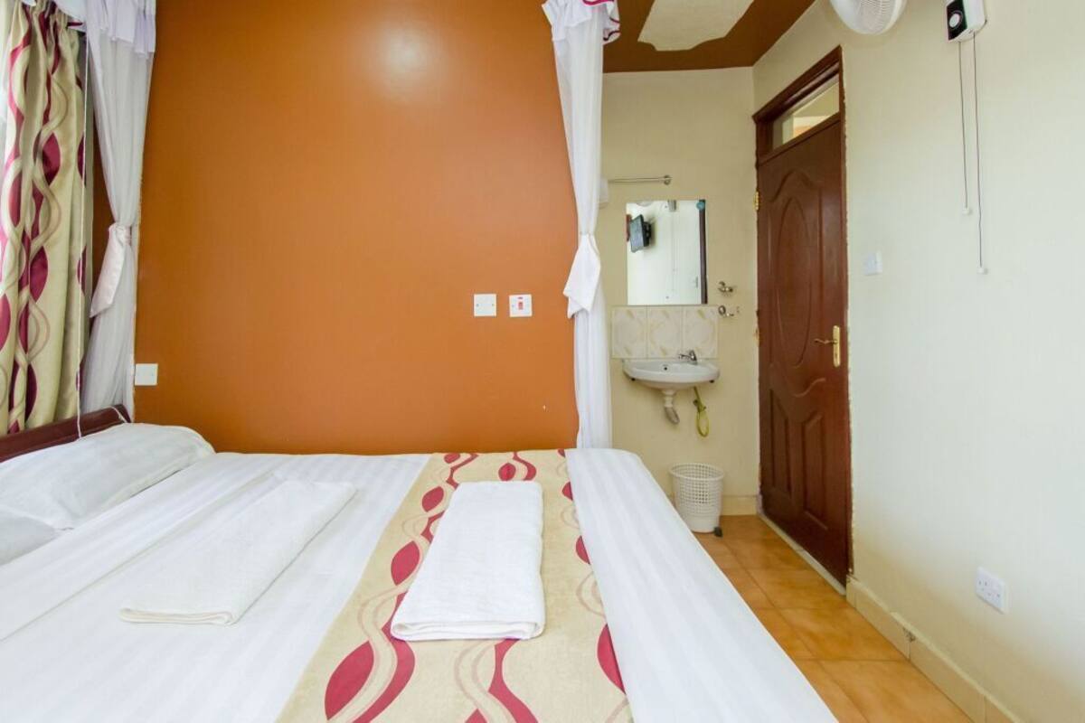 Une chambre d’hôtel avec deux lits, une salle de bain avec un lavabo et une porte.