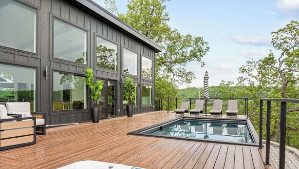 Une maison moderne dotée d’une terrasse en bois, d’un jacuzzi et d’une piscine.