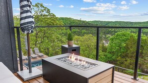 Un balcon doté d’un foyer intégré, de fauteuils confortables et offrant une vue sur un paysage verdoyant et luxuriant.